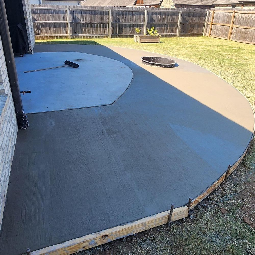 A concrete patio is being built in the backyard of a house.