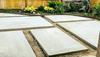 A concrete walkway is being built in a backyard.