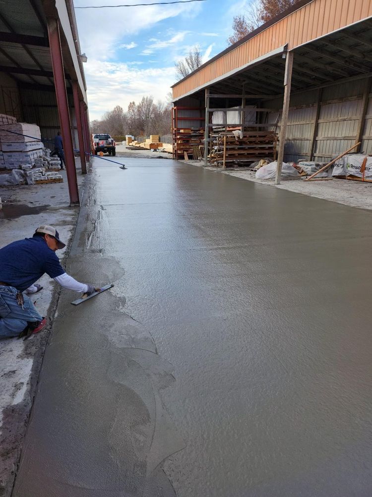 A man is kneeling down and spreading concrete on the ground.