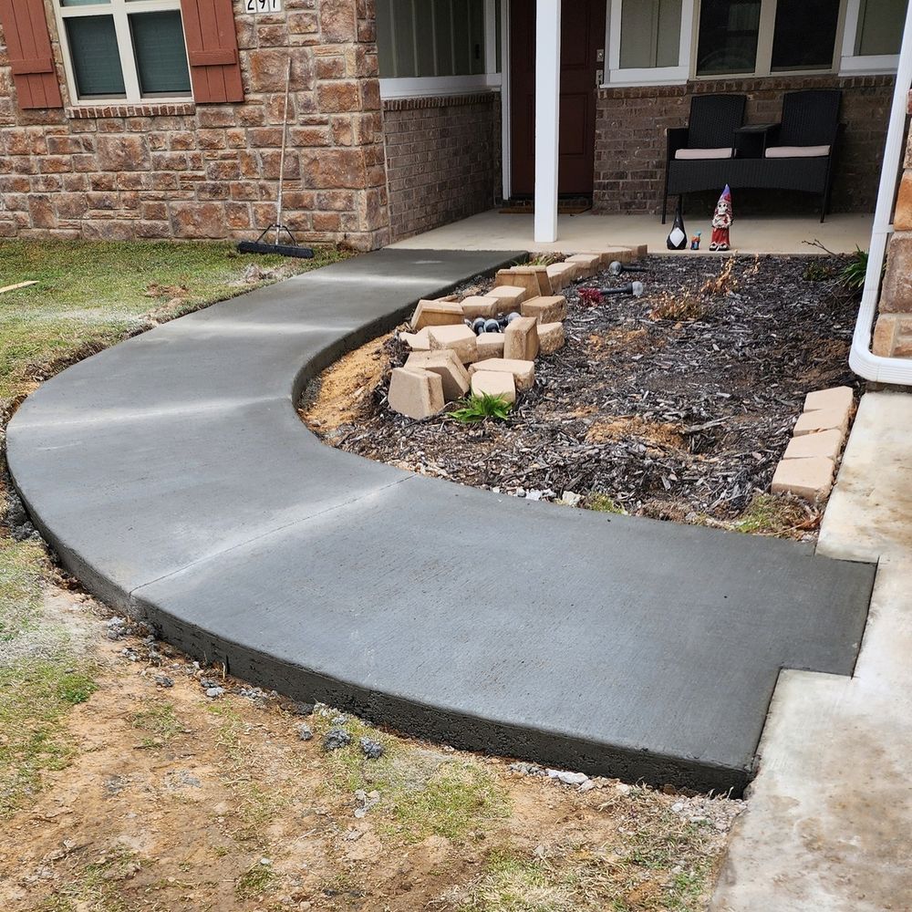 A curved concrete walkway is being built in front of a brick house.