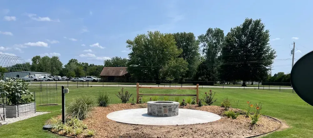 A fire pit is sitting in the middle of a grassy field.