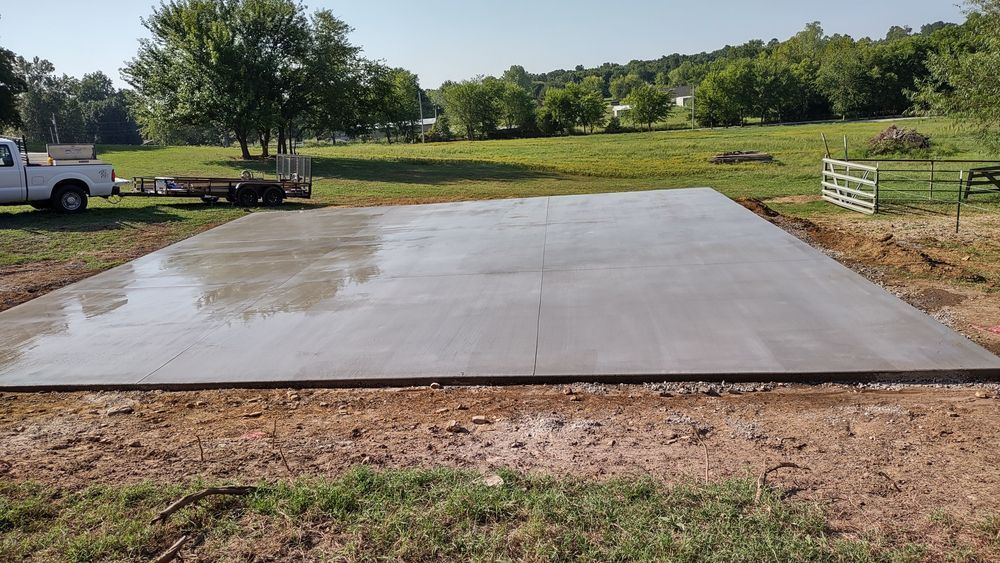 A white truck is parked on a concrete slab in a field.