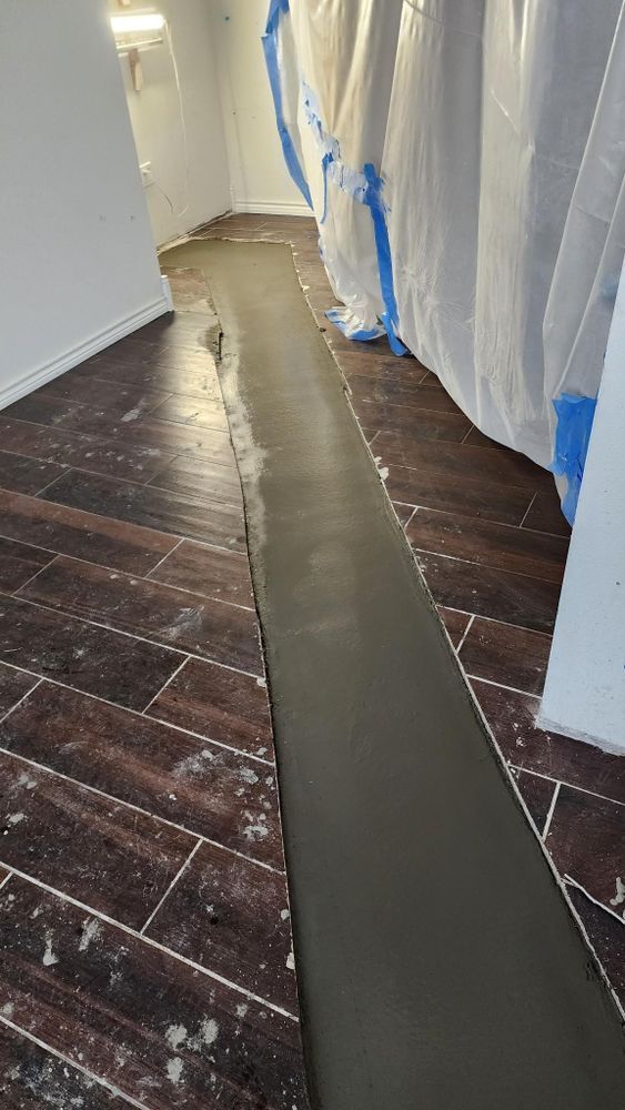 A concrete floor is being installed in a room with wooden floors.
