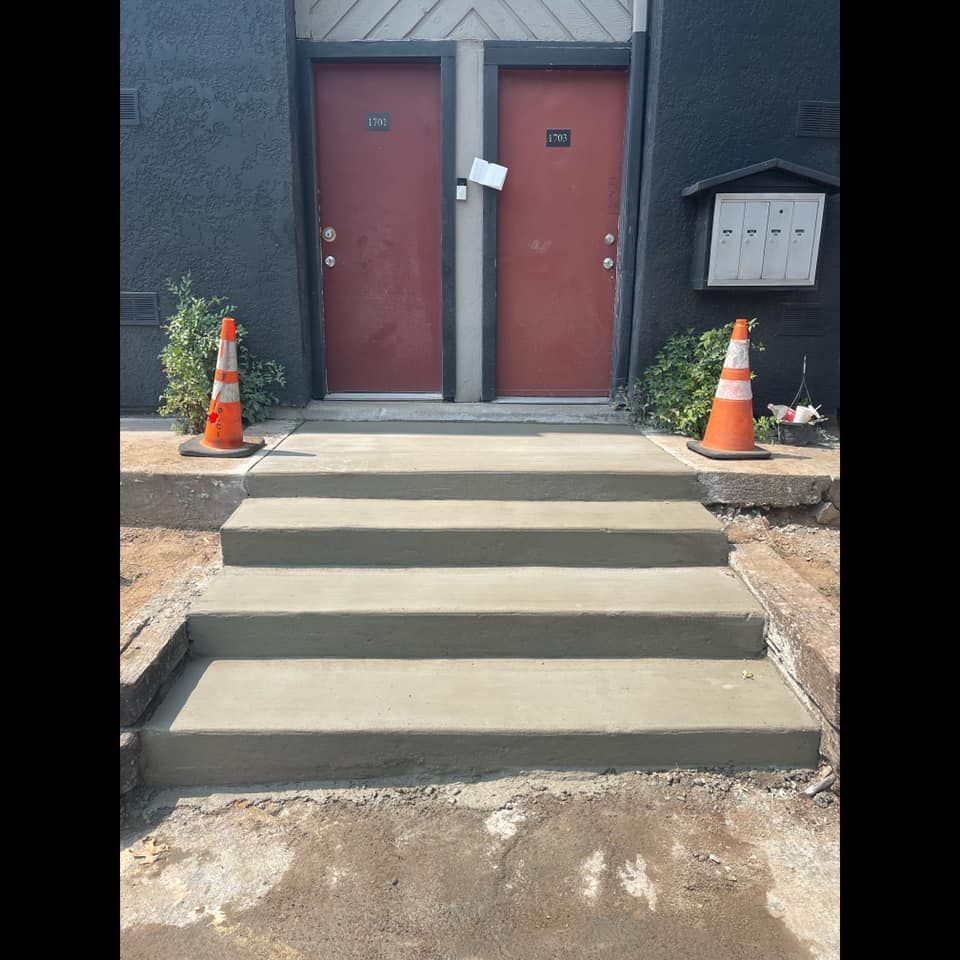 A set of concrete steps leading up to two red doors
