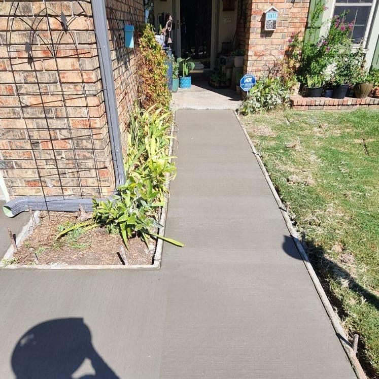 A concrete walkway is being built in front of a brick house.
