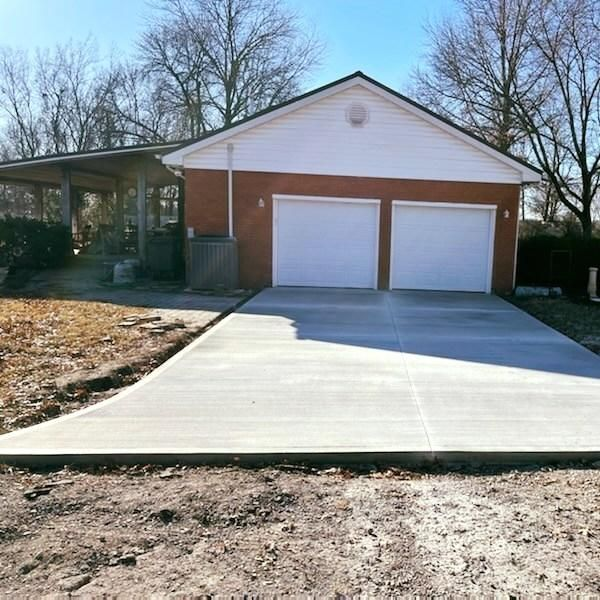 A brick garage with a concrete driveway in front of it.