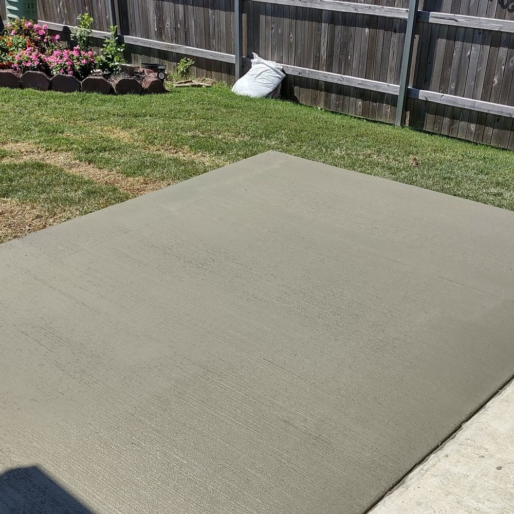 A concrete driveway with a wooden fence in the background.