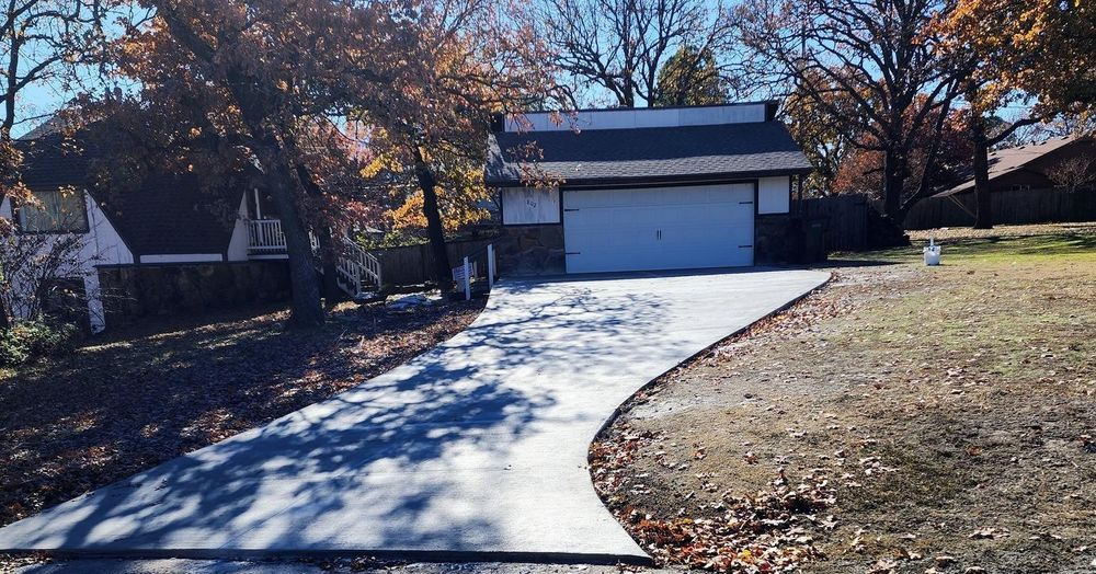 A driveway leading to a garage with a house in the background