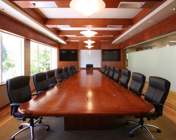 A conference room with a long wooden table and black chairs
