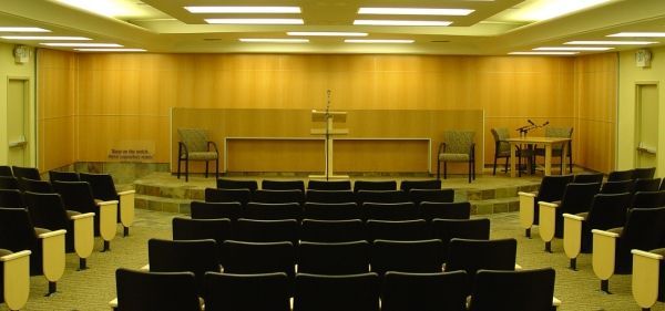 An auditorium with rows of black chairs and a podium