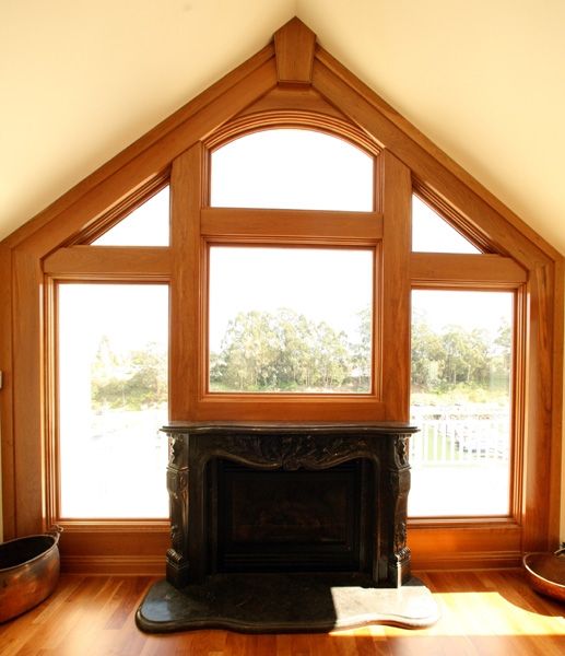 A fireplace in front of a large window with a vaulted ceiling