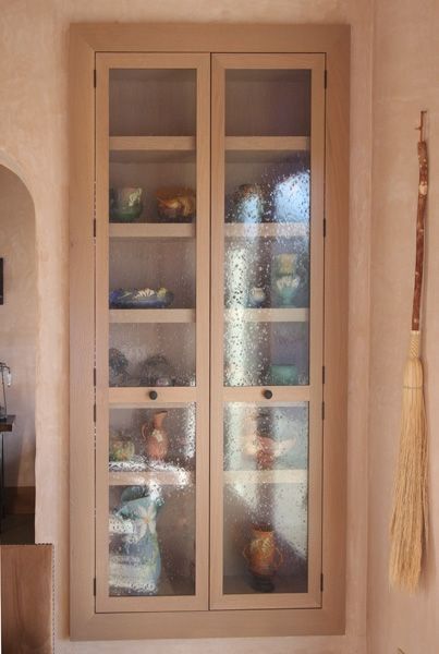 A cabinet with glass doors and shelves filled with vases