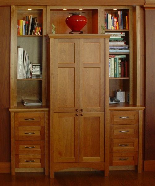 A bookcase with a red vase on top of it
