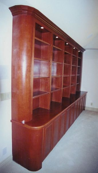 A very long wooden bookcase with lots of shelves