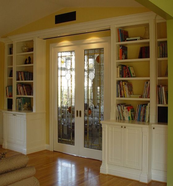 A living room with bookshelves and sliding glass doors