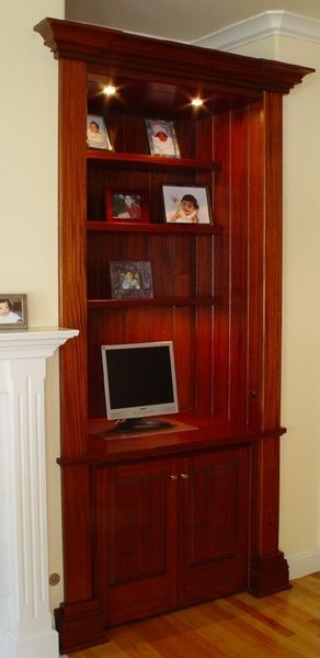 A wooden bookcase with a computer on top of it