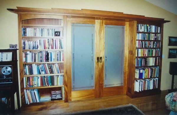 A living room with bookshelves and sliding glass doors