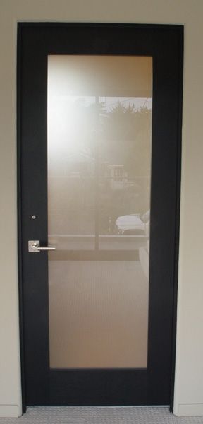 A black door with a clear glass window in a room.