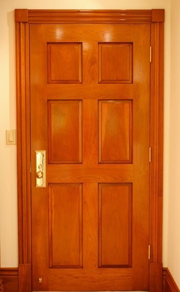 A wooden door with a gold handle is in a hallway