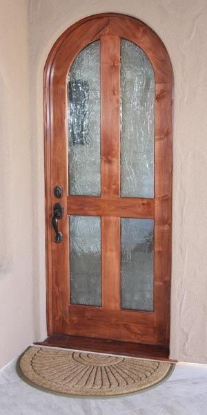 A wooden door with arched glass and a rug in front of it