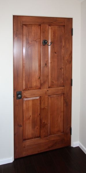 A wooden door in a room with a white wall