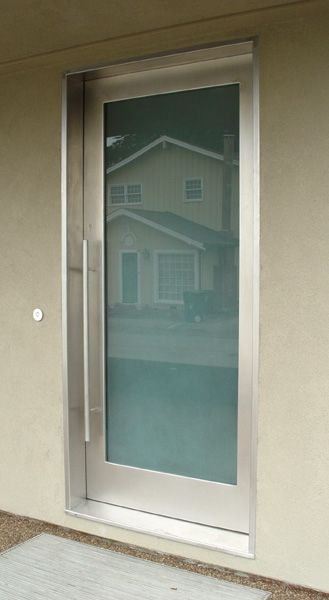 A stainless steel door with a reflection of a house in the glass.
