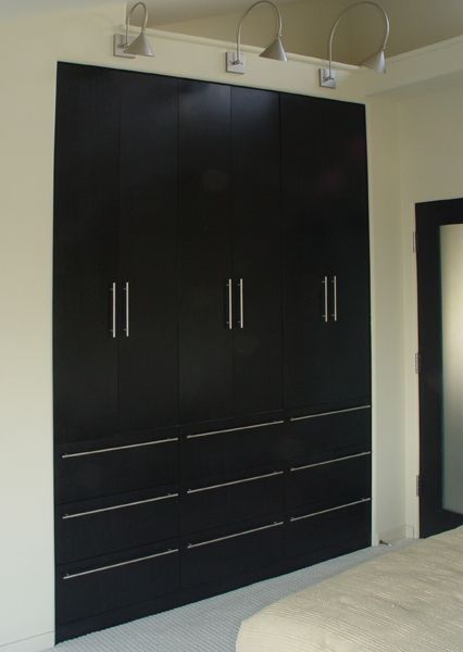 A bedroom with black cabinets and a bed