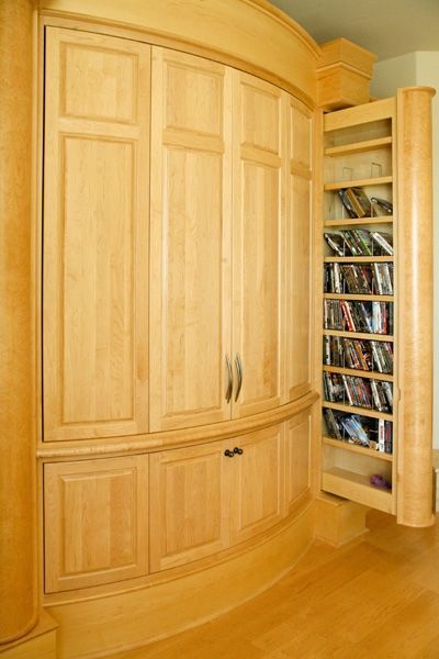 A wooden cabinet with a pull out shelf filled with dvds