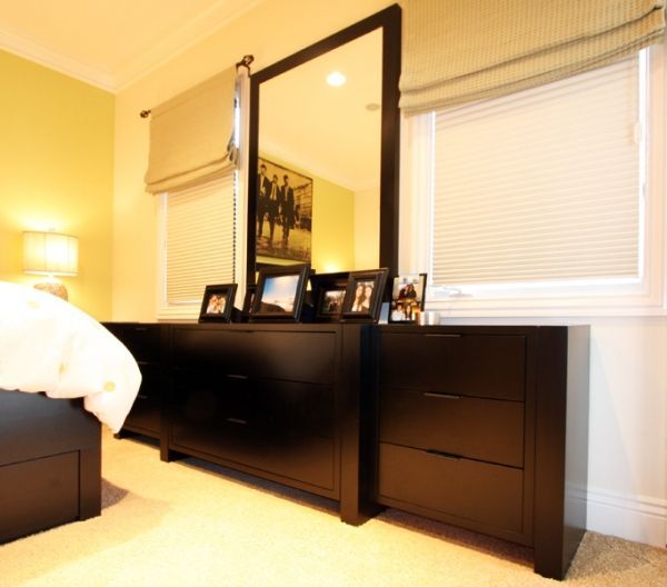 A bedroom with a dresser and a large mirror