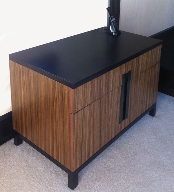A wooden cabinet with a black top and drawers