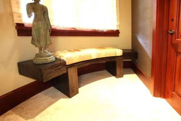 A statue of a woman sits on a wooden bench in a hallway