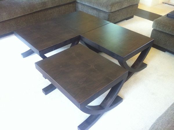 Three wooden tables are stacked on top of each other in a living room