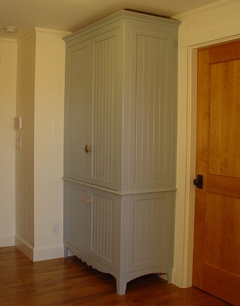 A gray cabinet is in a room next to a door