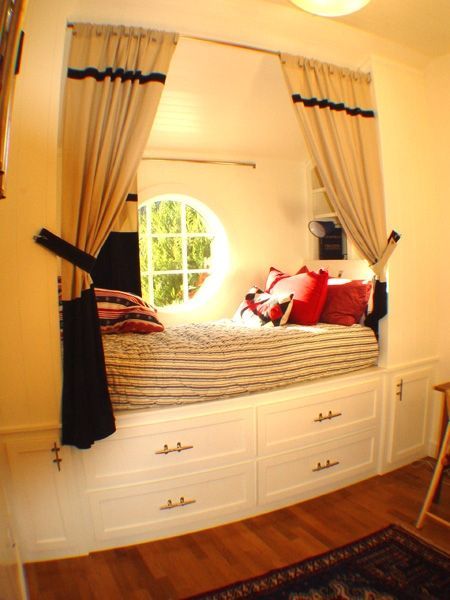 A bed in a corner of a room with a round window