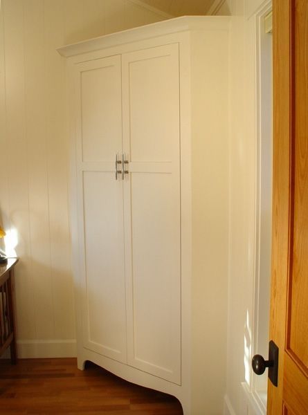 A white wardrobe is in a room next to a window