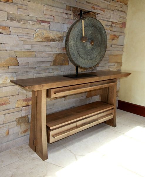 A wooden table in front of a stone wall