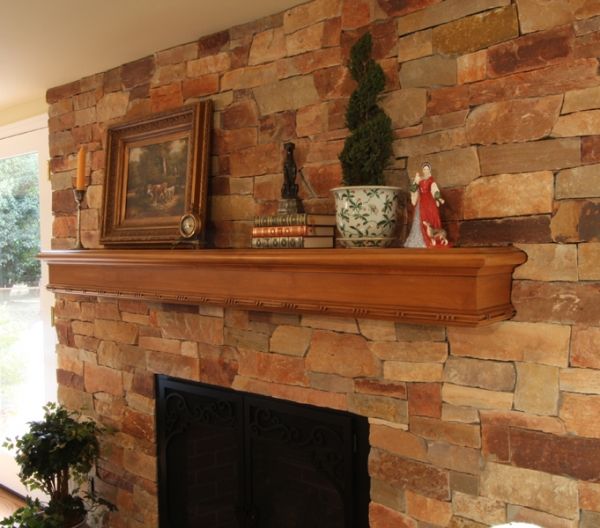 A fireplace with a stone wall and a wooden mantle