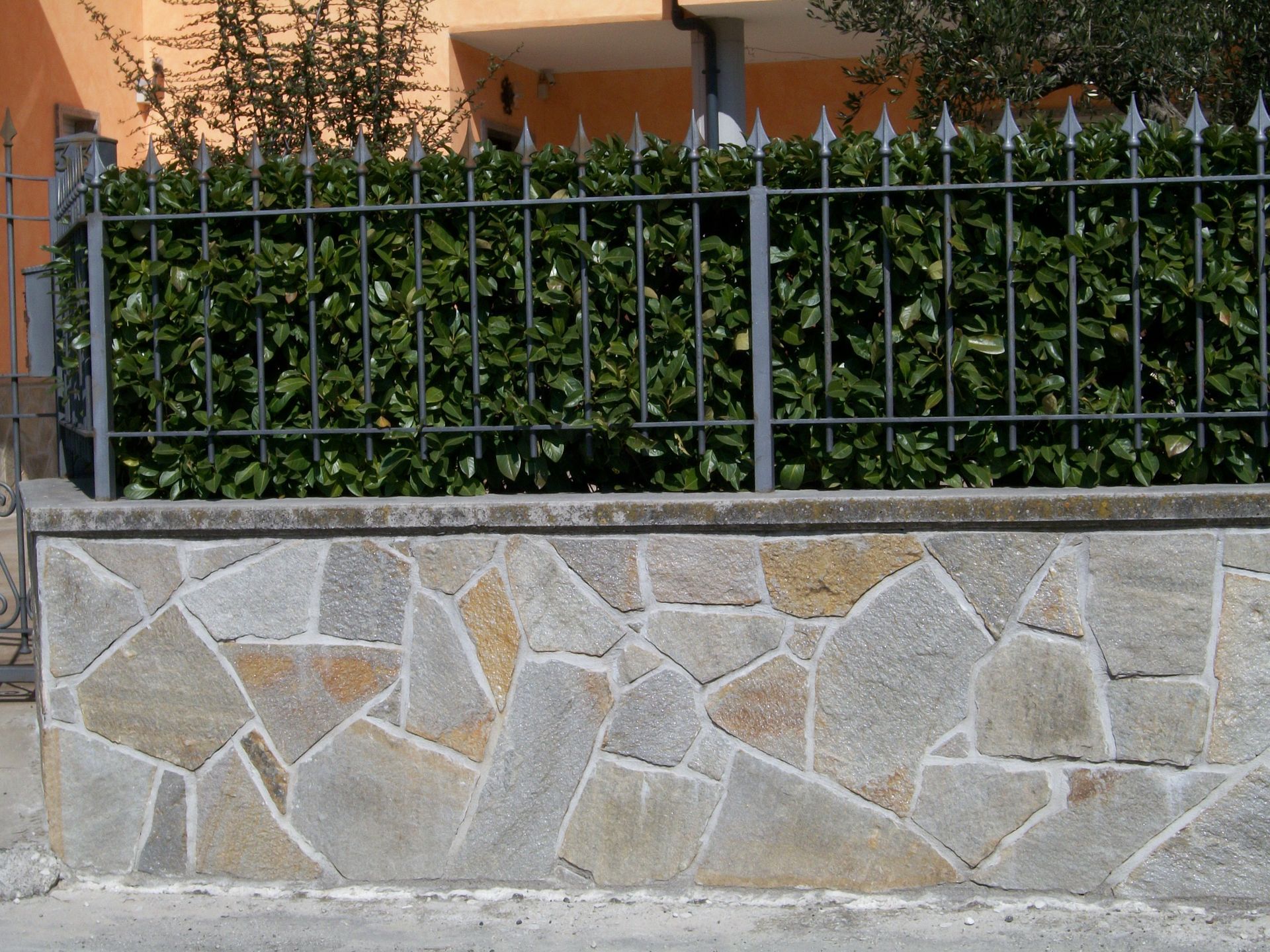 Un muro di pietra con una recinzione in ferro battuto dietro