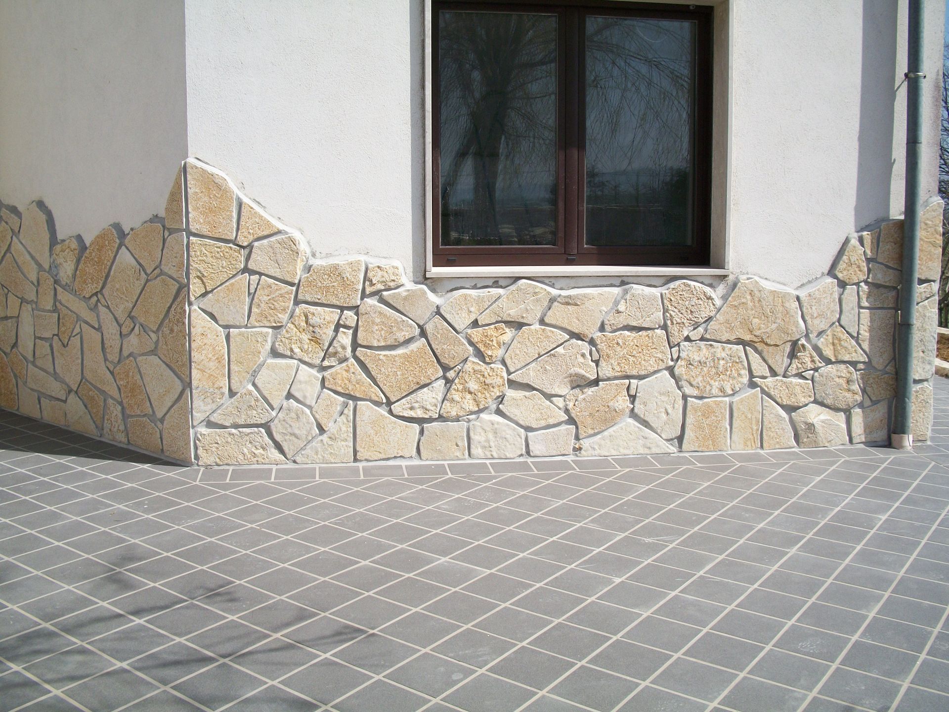 Un muro di pietra con una finestra sul lato di un edificio