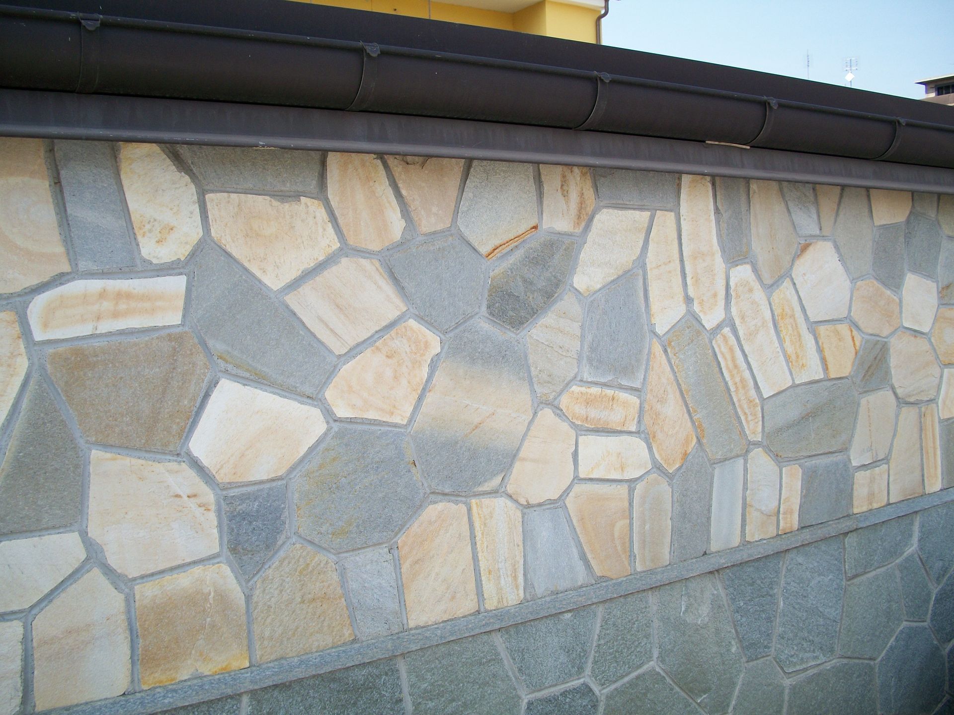 Un muro di pietra con una grondaia marrone sopra