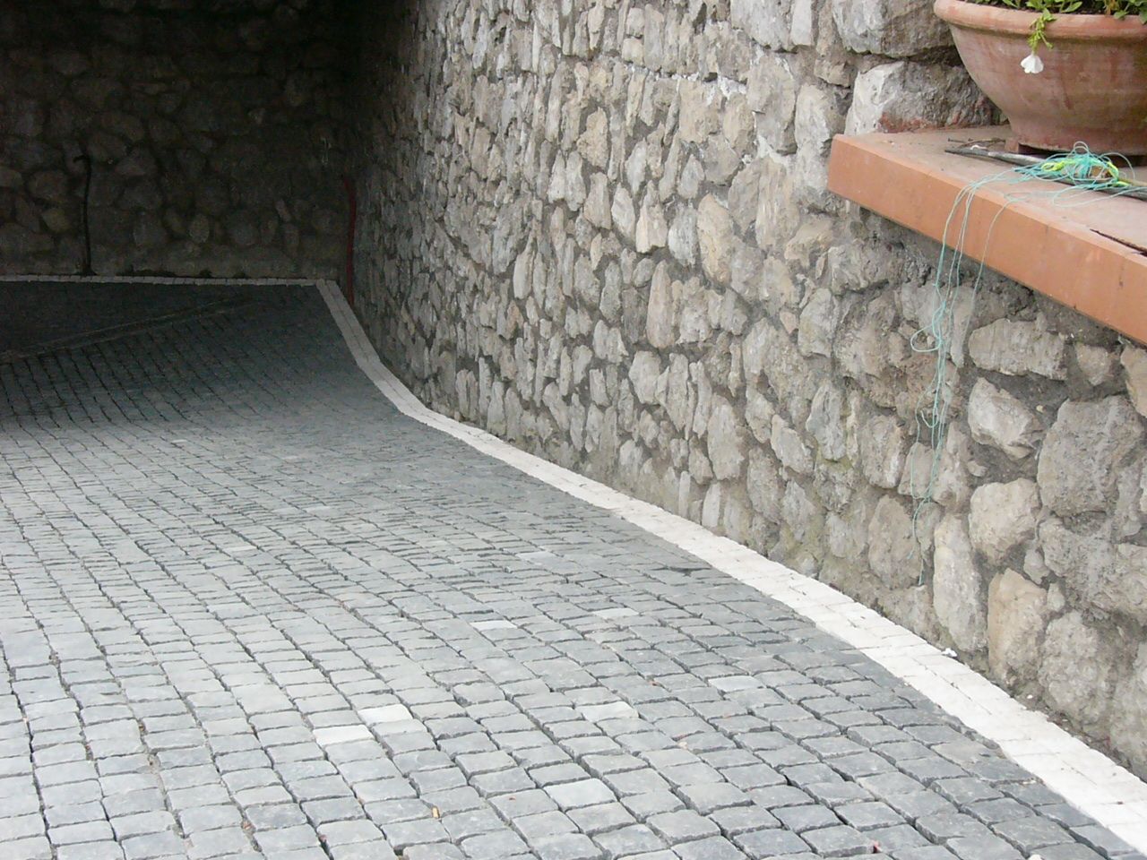 Un muro di pietra con un camminamento in mattoni che vi conduce