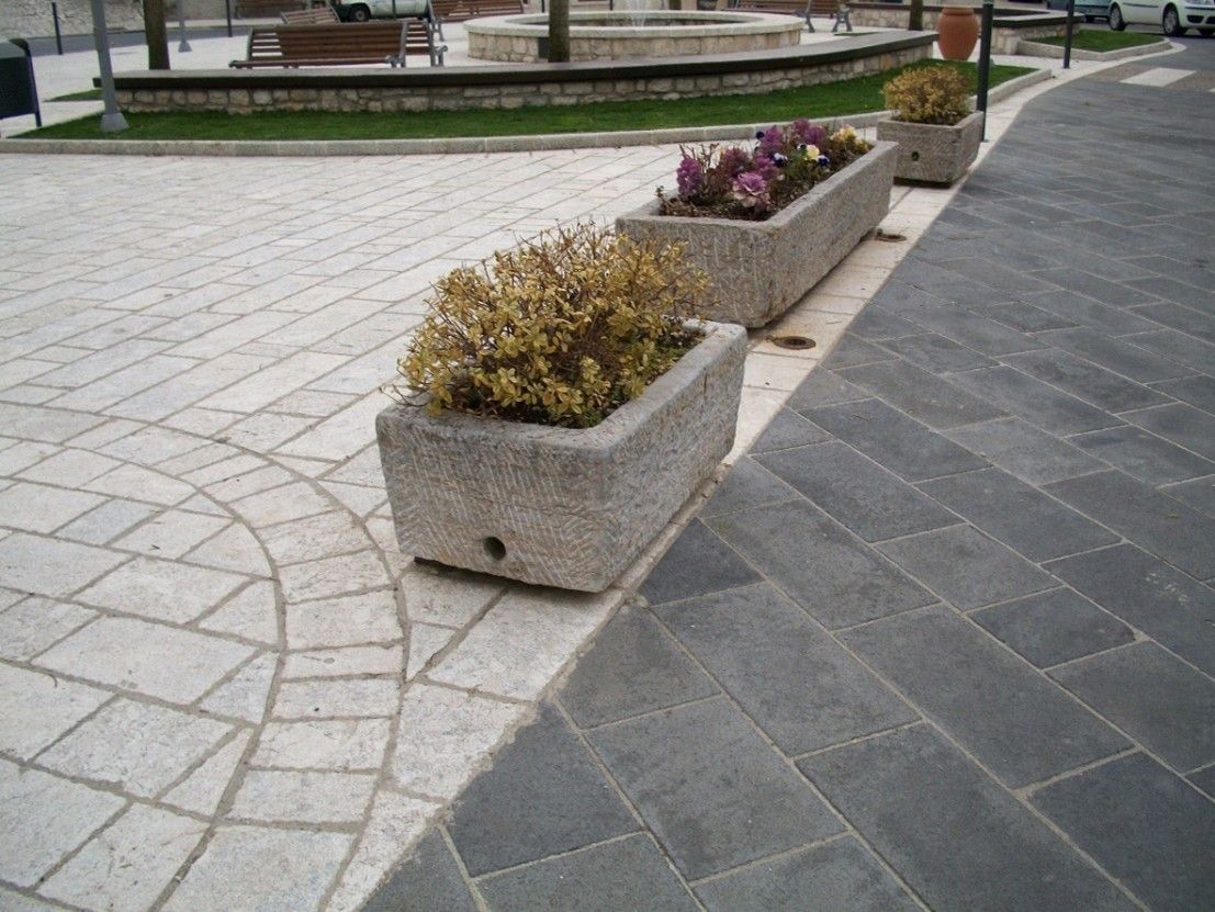 Una fila di fioriere su un marciapiede con fiori al loro interno