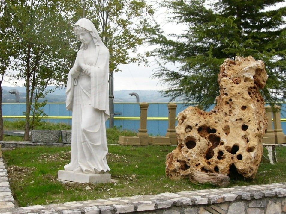 Una statua di una donna in piedi accanto a una grande roccia