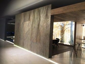 Una stanza con una grande parete, un tavolo e delle sedie.