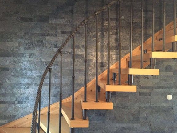 Una scala in legno con ringhiera in metallo contro un muro di mattoni