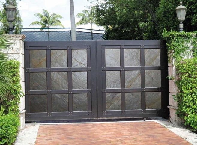 Un cancello nero con un camminamento in mattoni che vi conduce.