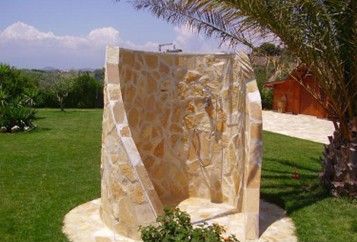 Una doccia di pietra si trova in mezzo a un lussureggiante campo verde.