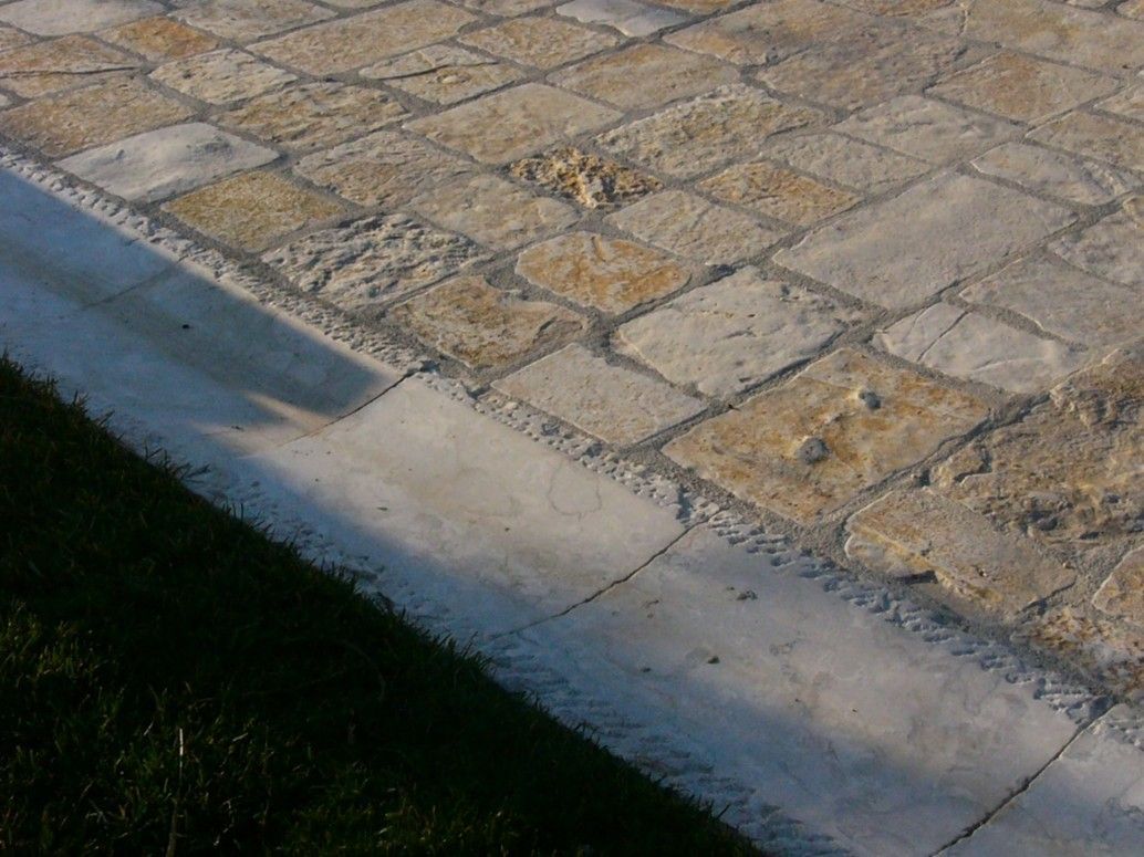 Primo piano di un marciapiede in pietra con un cordolo bianco.