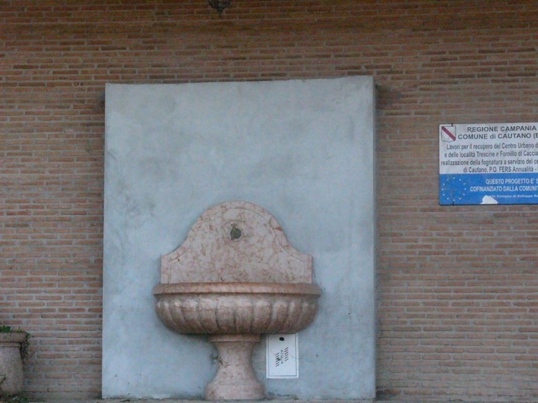 Un muro di mattoni con una fontana e un cartello sopra