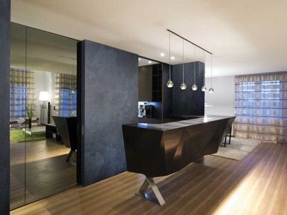 Una cucina moderna con un piano di lavoro nero e un pavimento in legno